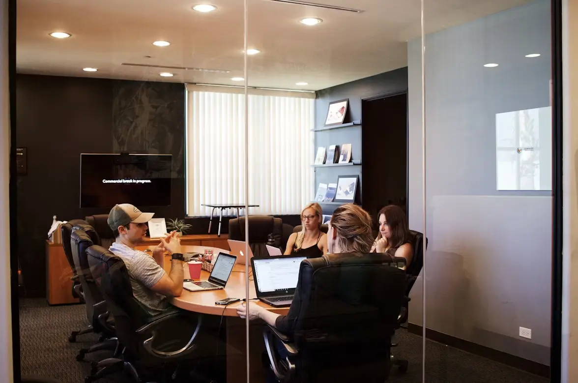 Modern office: two managers review a workflow and data on screen, without futuristic styling