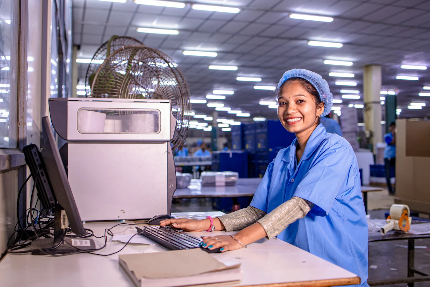 Factory worker entering production data on a computer next to the line